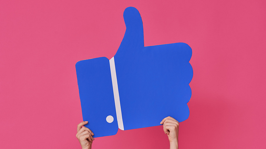 Giant Facebook "like" icon being held up by a person