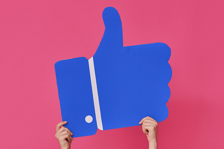 Giant Facebook "like" icon being held up by a person