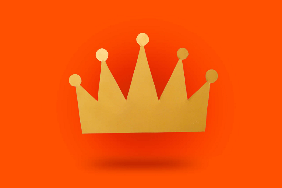 A golden paper crown on an orange background